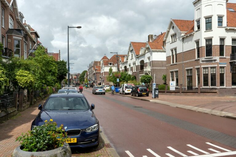 Straße mit alten Wohnhäusern, Autos, Bäume, Backsteingebäude