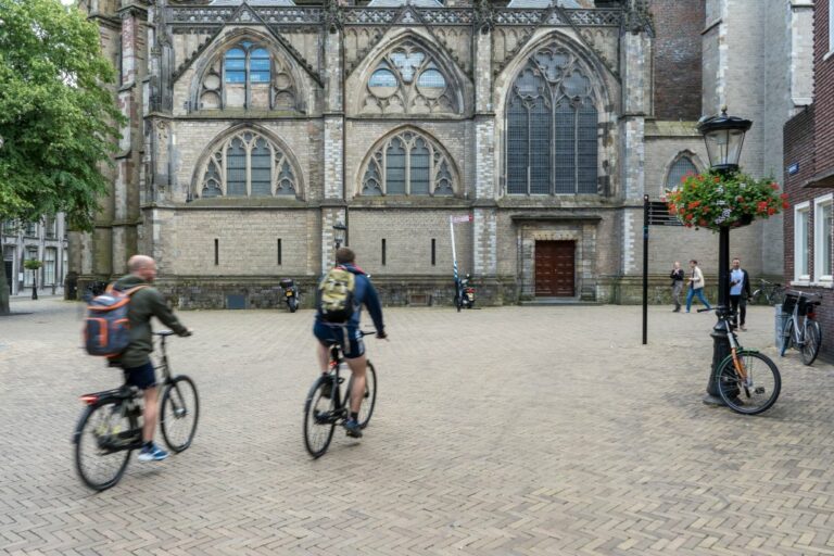 zwei Radfahrer fahren in Richtung einer gotischen Kirche