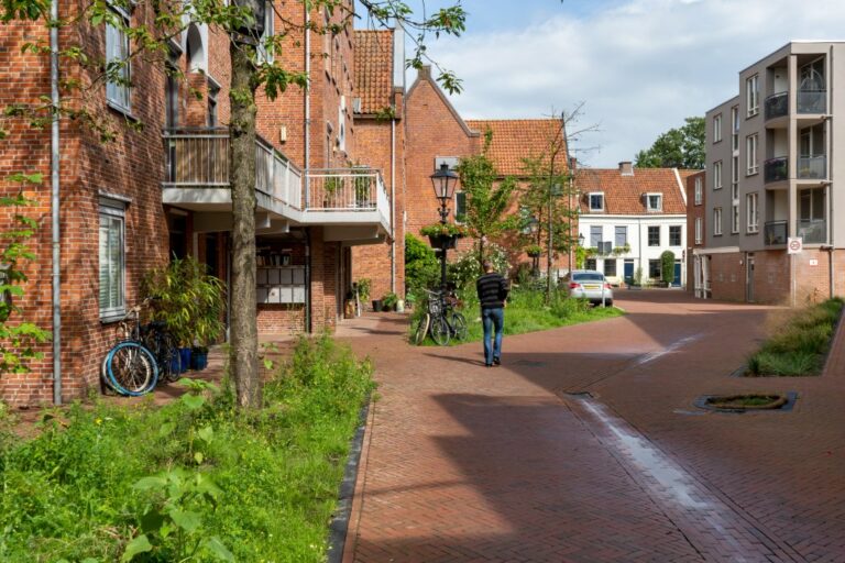 Mann geht durch eine Gasse in Utrecht, kleine Häuser, Grünflächen