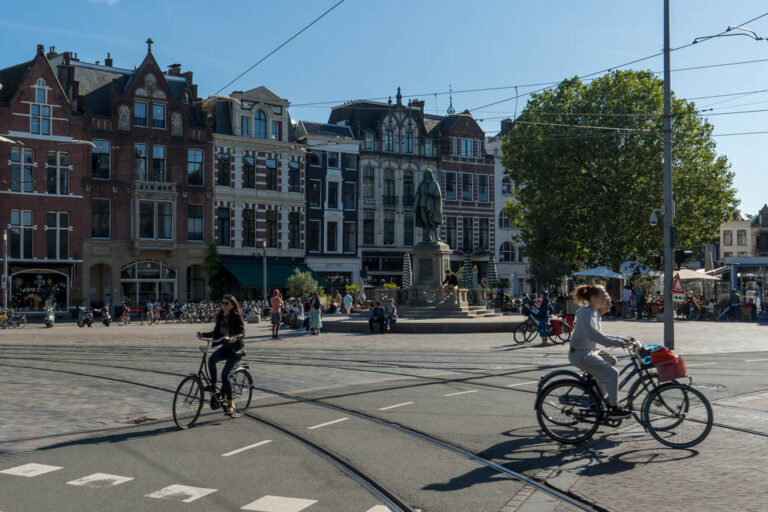Radfahrerinnen auf einer Kreuzung, Schienen, Statue