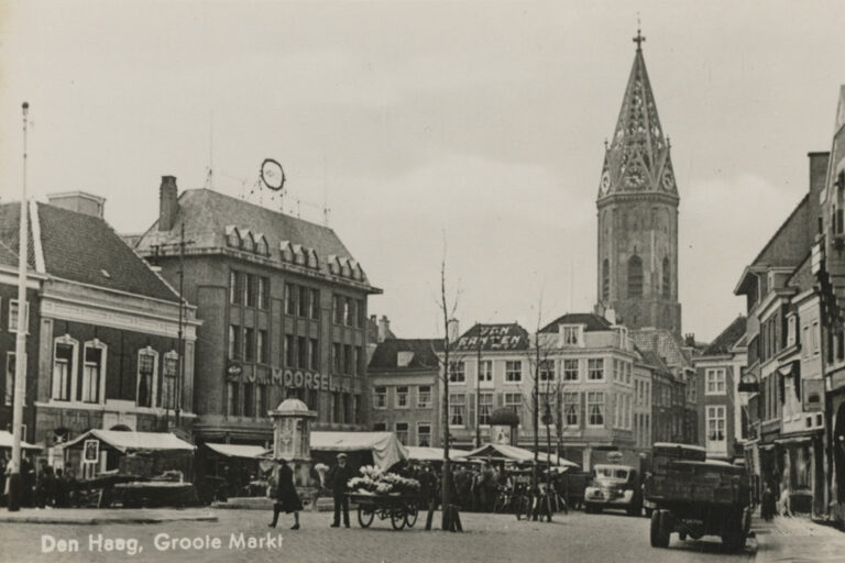 alte Aufnahme eines Marktplatzes mit Kirchturm und Autos