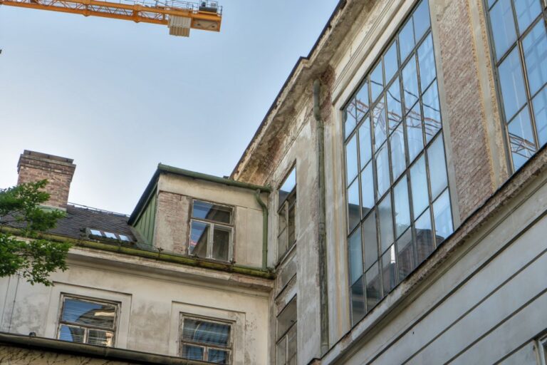 schadhafte Fassade eines Gebäudes in Wien, Kran