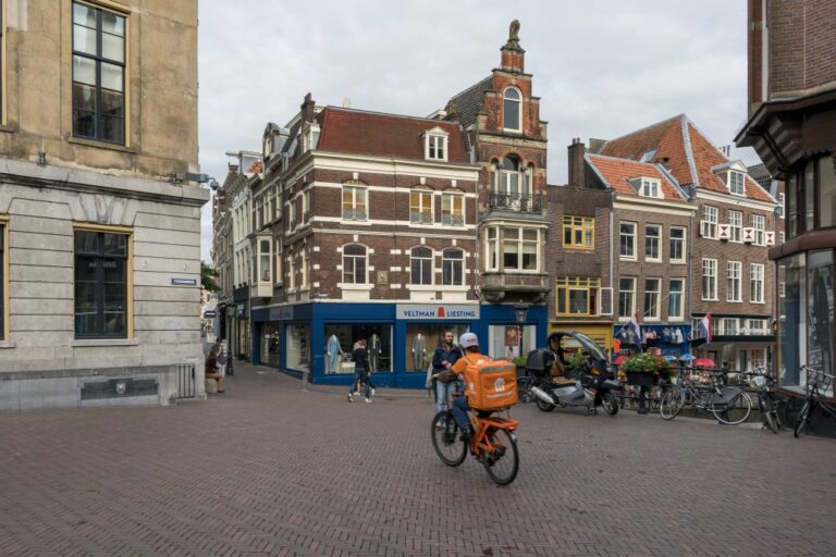 Fahrrad-Lieferdienst fährt am Rathaus von Utrecht vorbei