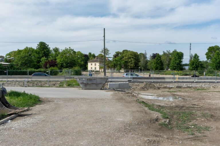 Straße mit Zäunen und Betonleitwänden in Wien-Donaustadt, Strommast