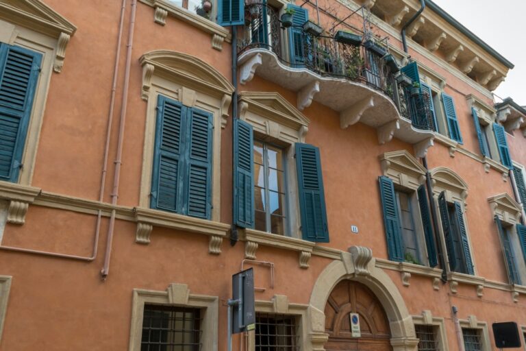 historisches Gebäude mit Balkon, hohen Fenstern und Fensterläden