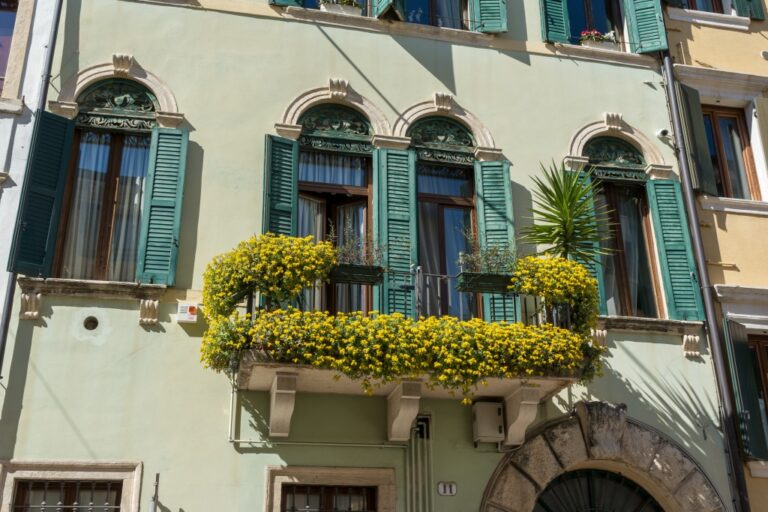 Balkon mit blühenden Pflanzen, historisches Gebäude, Fensterläden, Rundbögen, Verona