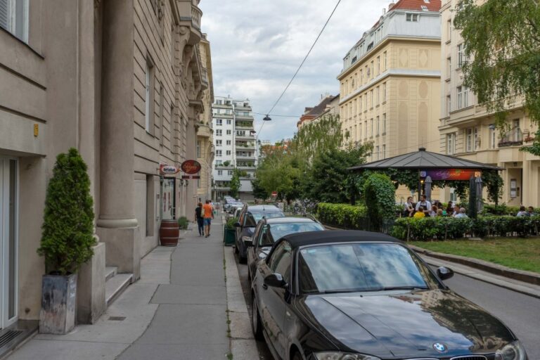 Platz in Wien-Landstraße, Grünflächen, parkende Autos, Häuser, Gastgarten, Leute