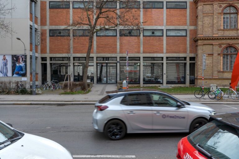 Straße vor einem Eingang einer Universität, Autos, Backsteinfassade, Baum