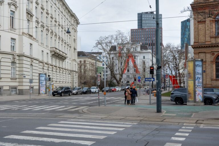 Kreuzung in Wien, Ringstraße, Leute warten an einer Ampel, alte Häuser, Hochhaus