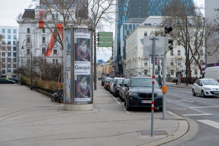 parkende Autos, Litfaßsäule, Verkehrszeichen, alte und moderne Häuser, Laternen, Straße